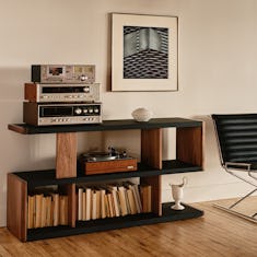 New Canaan Low Bookshelf designed by BassamFellows for Geiger in Walnut with Black Leather shown angled in a residential setting with books and objects on shelves.